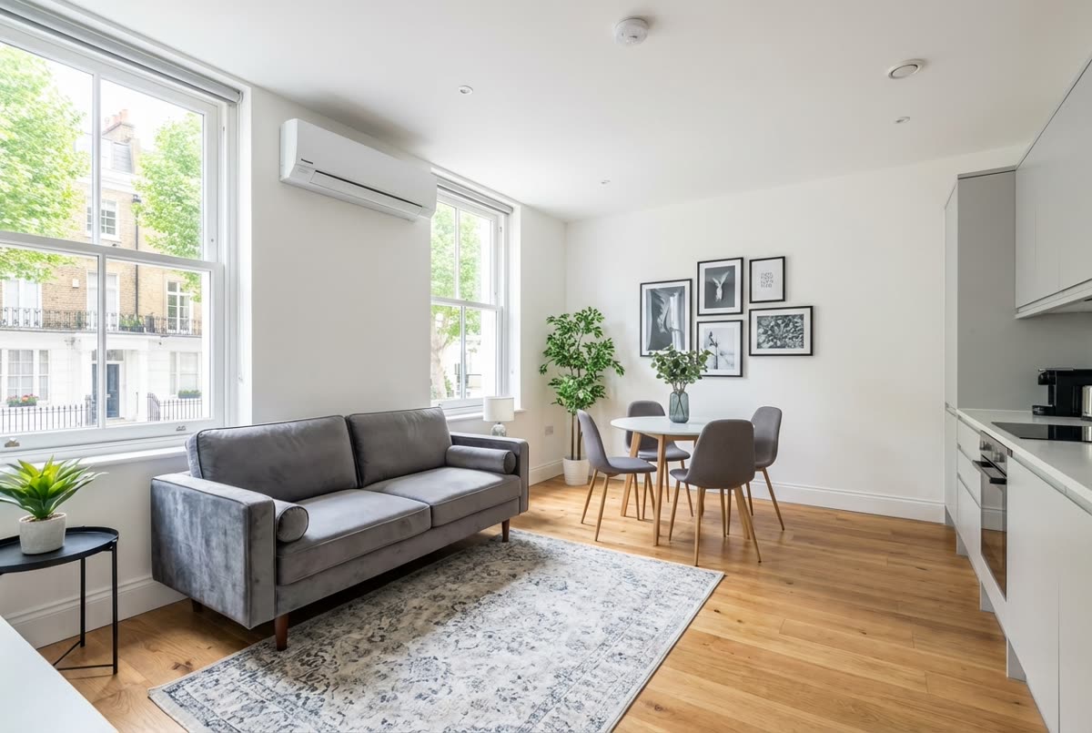 Bright London flat with slim white wall-mounted AC unit above sash windows — clean, furnished, modern interior